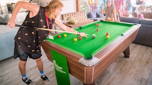 A pool table in a room with a sofa and a television in the background. - Marco Polo Malta Hostel (St. Julian's)