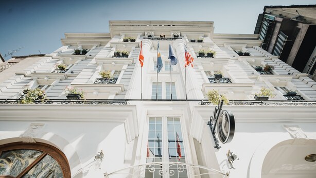 Un edificio imponente con fachada simétrica, ventanas amplias y una entrada central con un arco decorativo.
