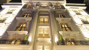 Un edificio imponente con amplias ventanas, balcones ornamentados y detalles arquitectónicos clásicos.