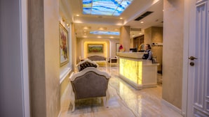 Un hall de hotel con mostrador de recepción, un sofá y un cuadro en la pared.