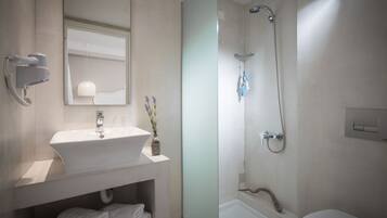 A modern bathroom with a white sink, mirror, and shower.