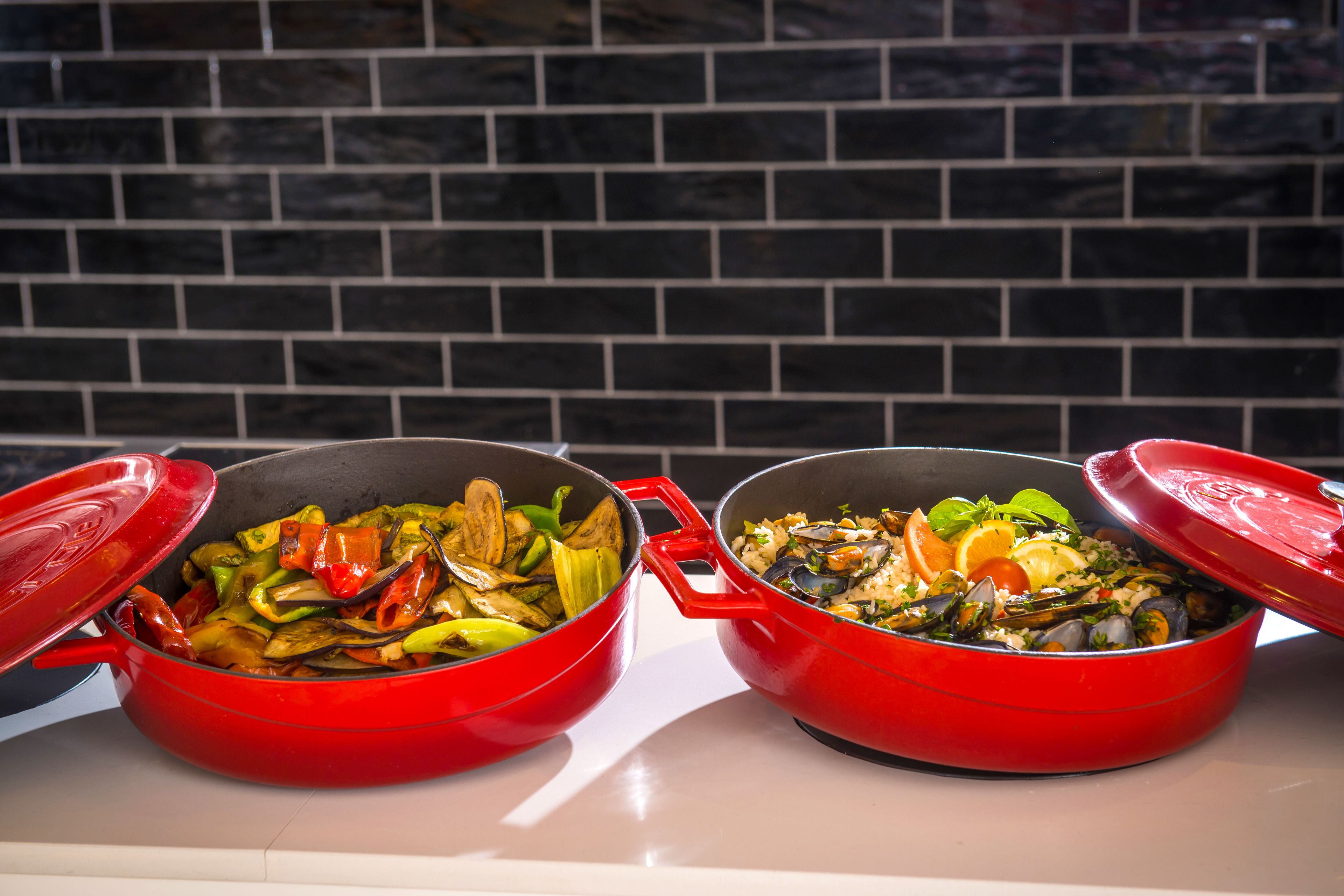 Two red pots with lids on a white countertop.