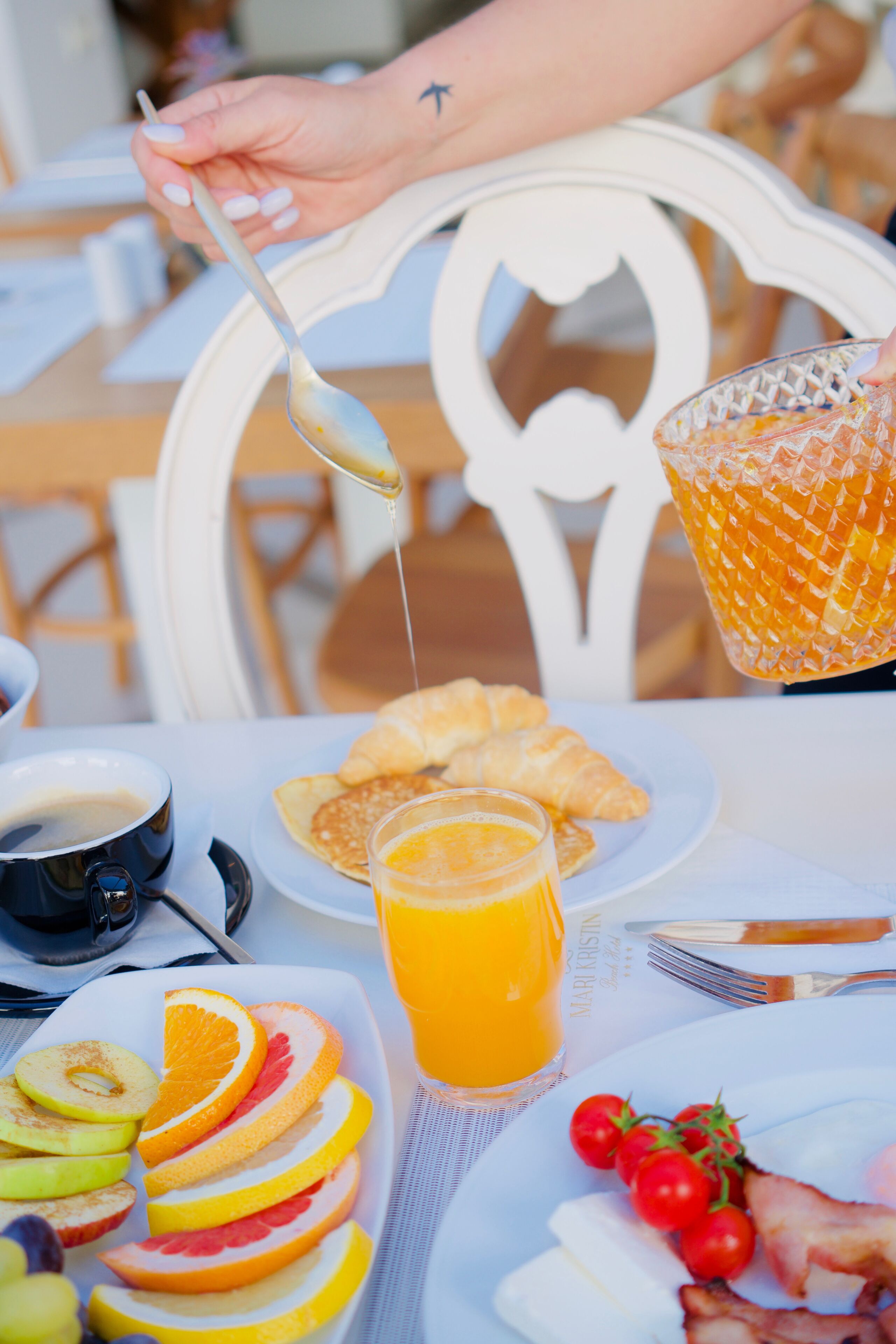 Desayuno con cruasanes, fruta y jugo de naranja sobre una mesa.