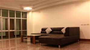 Una habitación moderna con un sofá marrón oscuro, una pequeña mesa de madera y un muro divisorio de vidrio.