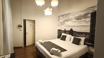 A hotel room with a bed, a view of the cityscape, and a ceiling with exposed beams.