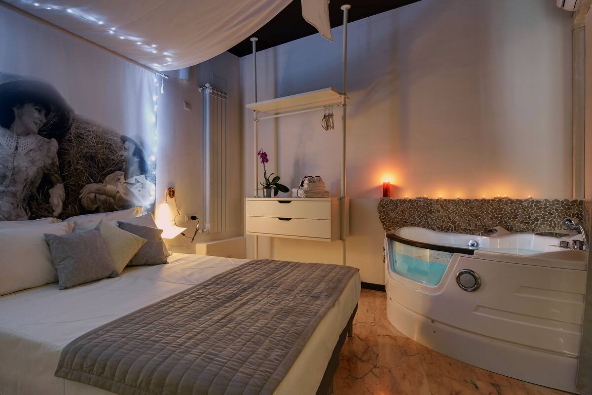Un dormitorio con cama, mesita de noche y bañera integrada.