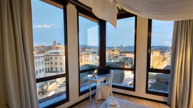 Une chambre d’hôtel moderne dotée de grandes fenêtres, d’un lit, d’un bureau et d’une chaise.