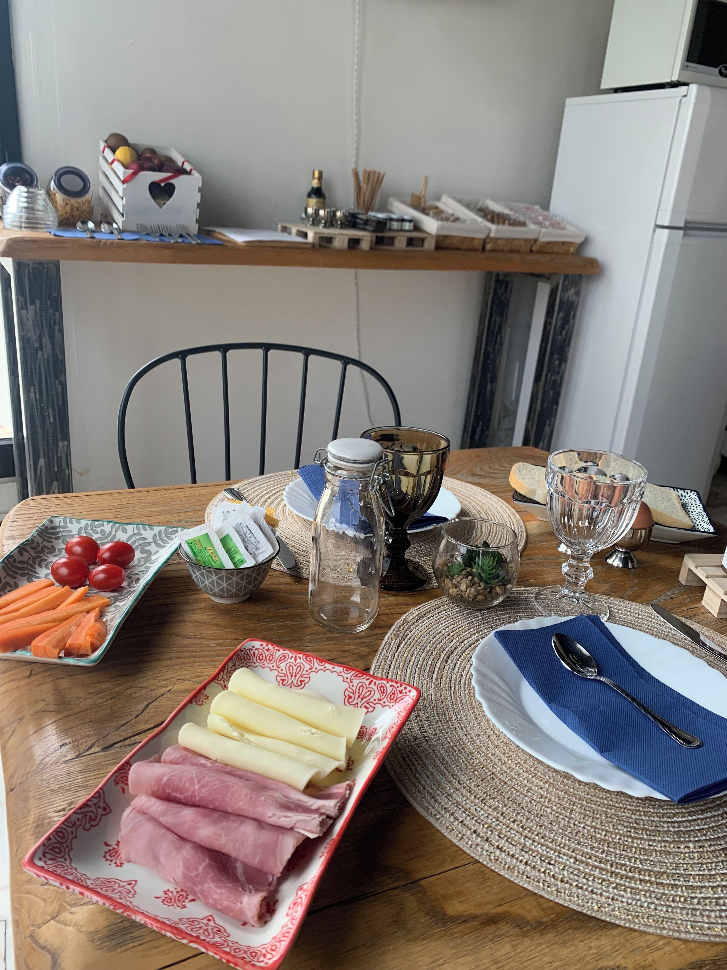 A dining table with various food items, a chair, and a kitchen area in the background.