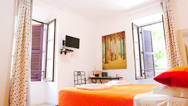 Un dormitorio con cama, escritorio, silla, televisor y un cuadro en la pared.