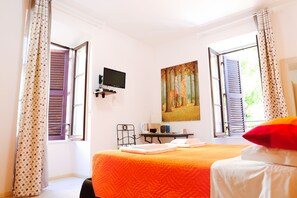 A bedroom with a bed, a desk, a chair, a television, and a painting on the wall. - Your Rome (Rome)