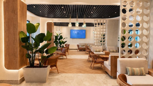 En modern entréhall med trämöbler, krukväxter, en tv-skärm och en unik, cirkelformad väggdesign.