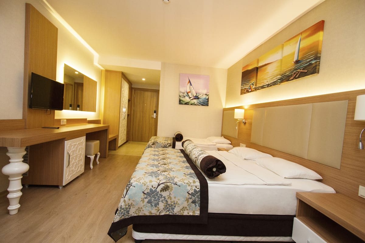A hotel room with a bed, a desk, a television, and artwork on the walls.