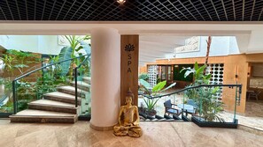 Un espacio de spa con una estatua de Buda, una escalera y plantas de interior.