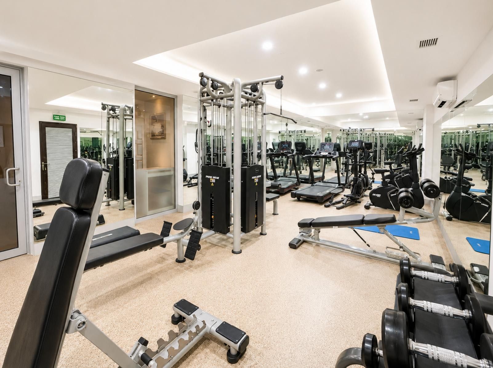 A gym with various exercise equipment, including treadmills, weight machines, and free weights.