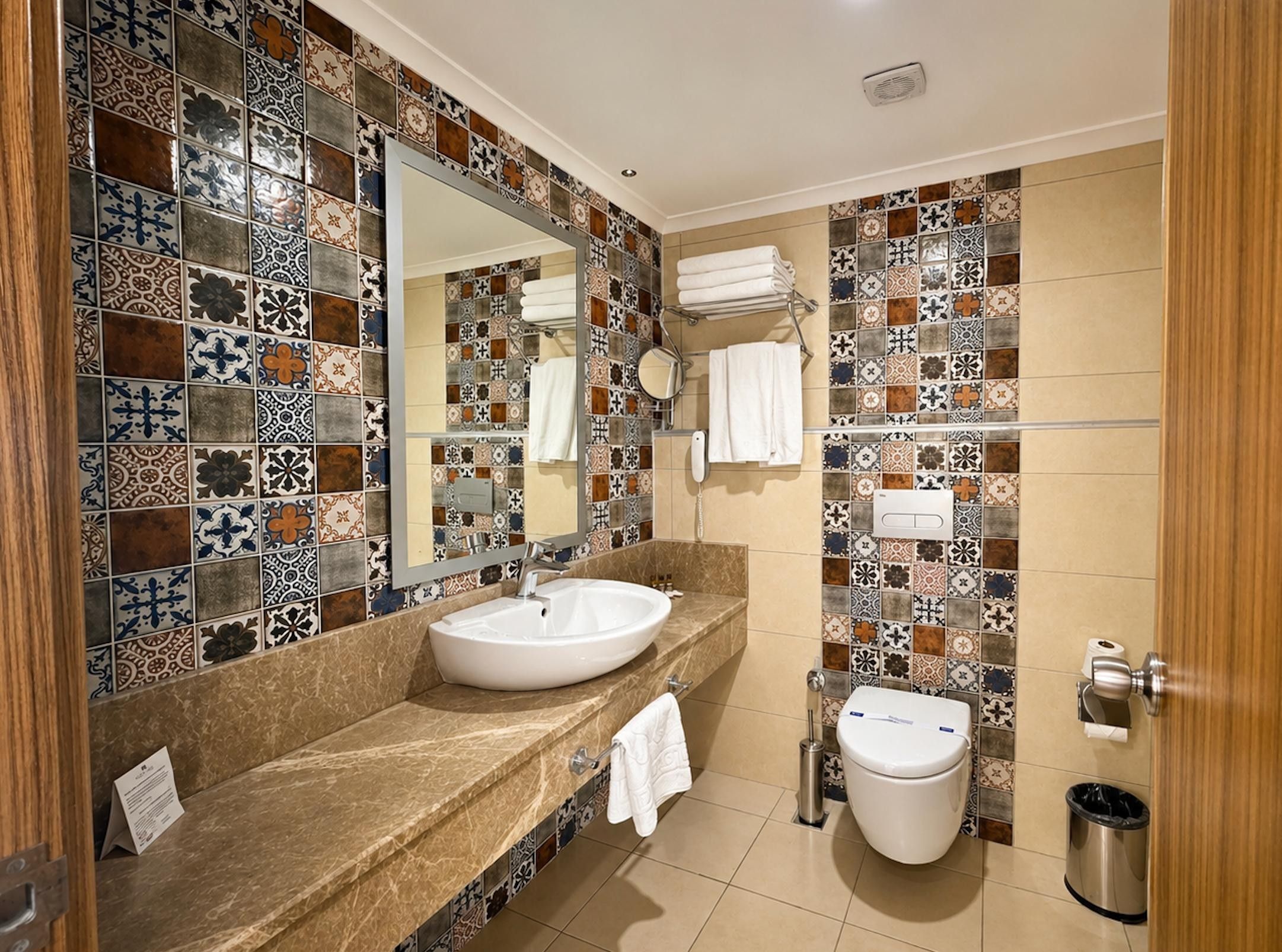 A bathroom with a marble sink, a toilet, and a mirror.