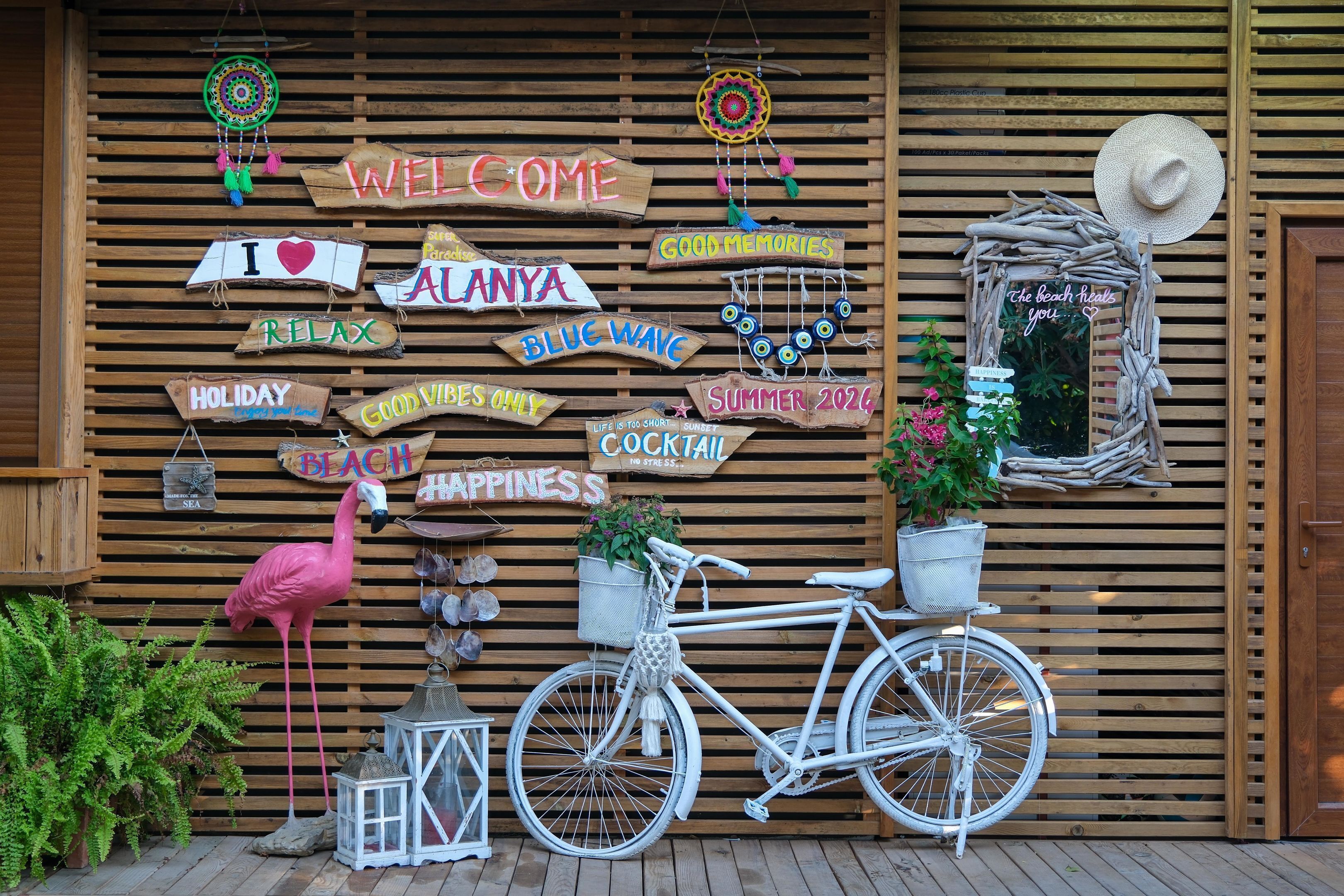 Eine Holzwand mit verschiedenen Schildern und Dekorationen, darunter ein Fahrrad und ein Flamingo.