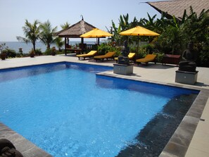Una piscina al aire libre, sombrillas, sillones reclinables de piscina