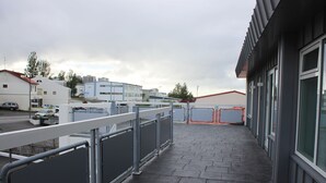 Un edificio con un paseo empedrado, barandillas metálicas y amplios ventanales.