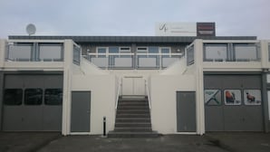 Un edificio con un letrero que dice 'LUXAPARTIS' y 'Apartamentos Mini Lujo'. Se observan dos escaleras que conducen a un segundo piso con ventanas.