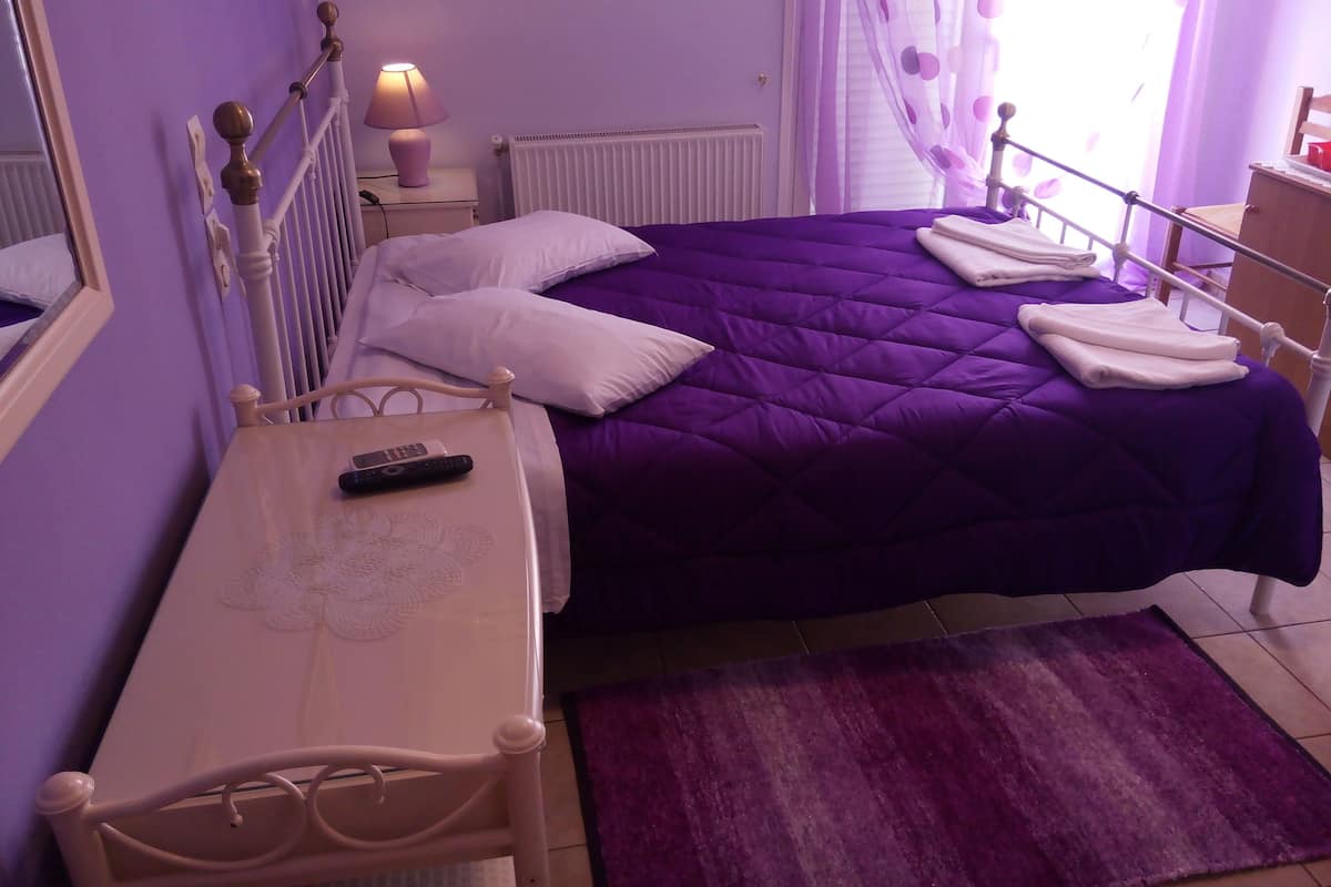 A bedroom with a bed, a bedside table, a lamp, and a window with curtains.