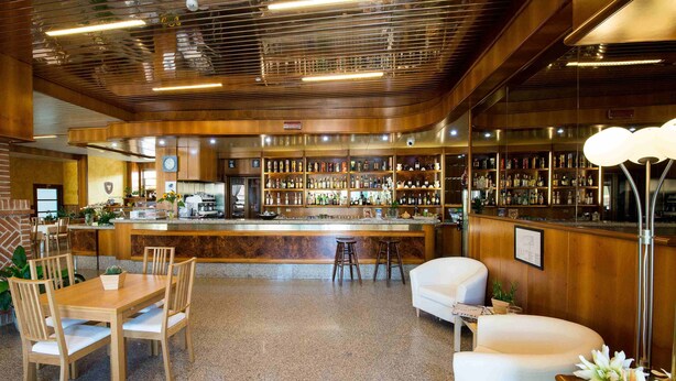 A bar area with wooden paneling, a counter, and seating. - Hotel Route 9 (Cadeo)