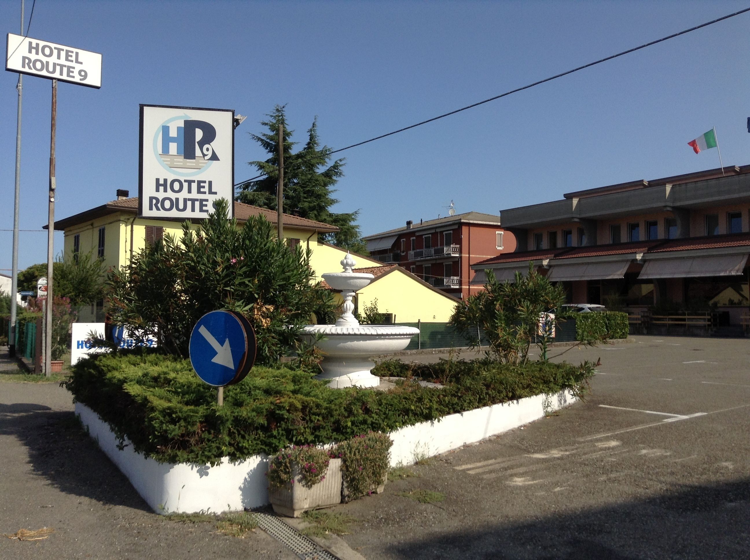 Ein Hotelschild mit der Aufschrift "HOTEL ROUTE 9" und einem blauen Hinweisschild, das eine Linkskurve anzeigt.