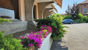A building with a covered outdoor area, concrete steps, and flower beds with pink and yellow flowers. - Hotel Route 9 (Cadeo)