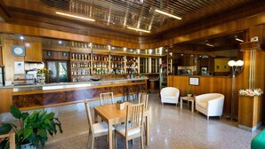 A bar area with wooden furnishings, a counter, and a seating area with chairs and a sofa. - Hotel Route 9 (Cadeo)