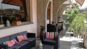 An outdoor seating area with wicker furniture, cushions, and a lantern. - Hotel Route 9 (Cadeo)
