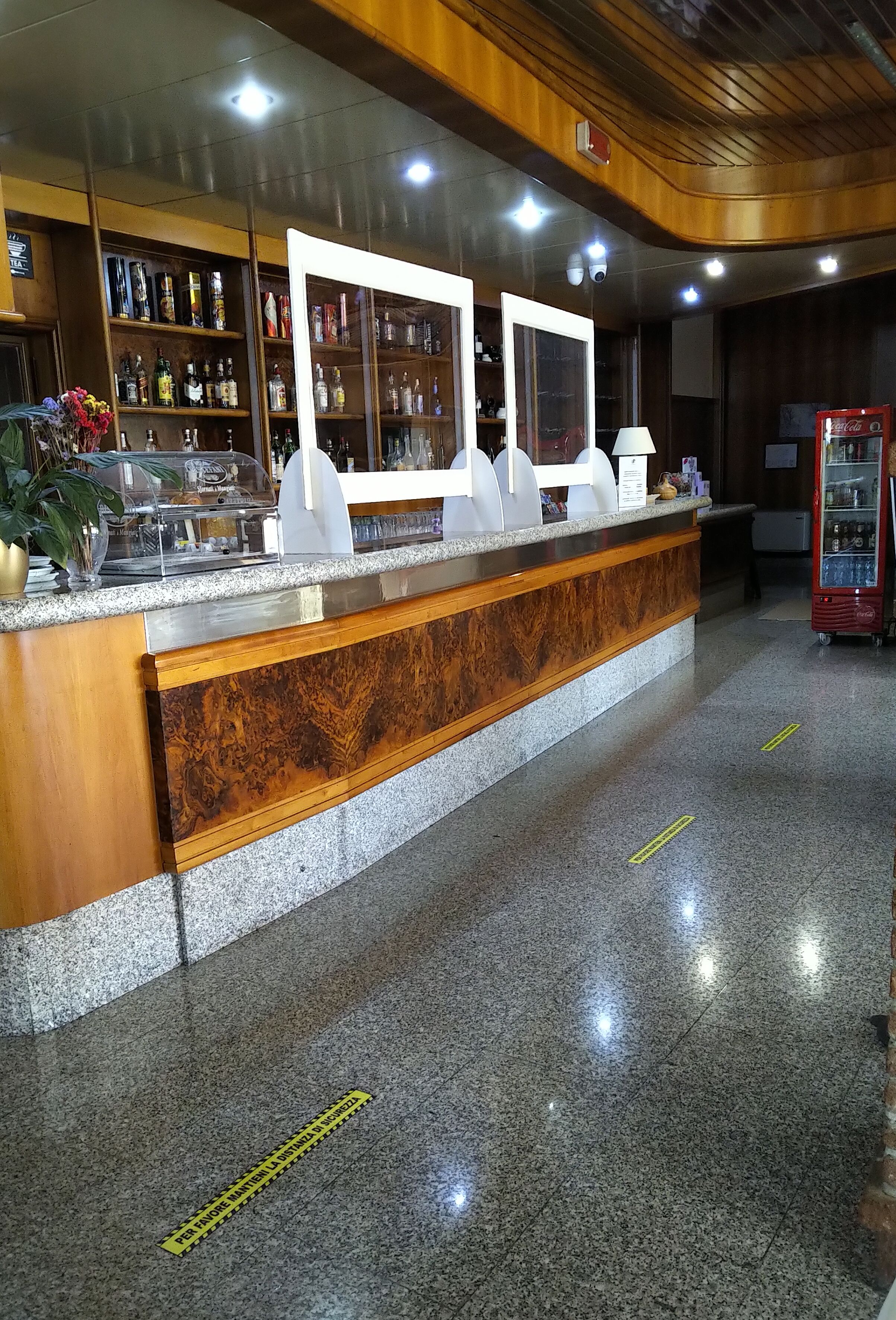 Un área de recepción con un mostrador de madera, vitrinas de vidrio y una máquina expendedora de Coca-Cola.