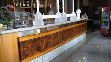 Un área de recepción con un mostrador de madera, vitrinas de vidrio y una máquina expendedora de Coca-Cola.