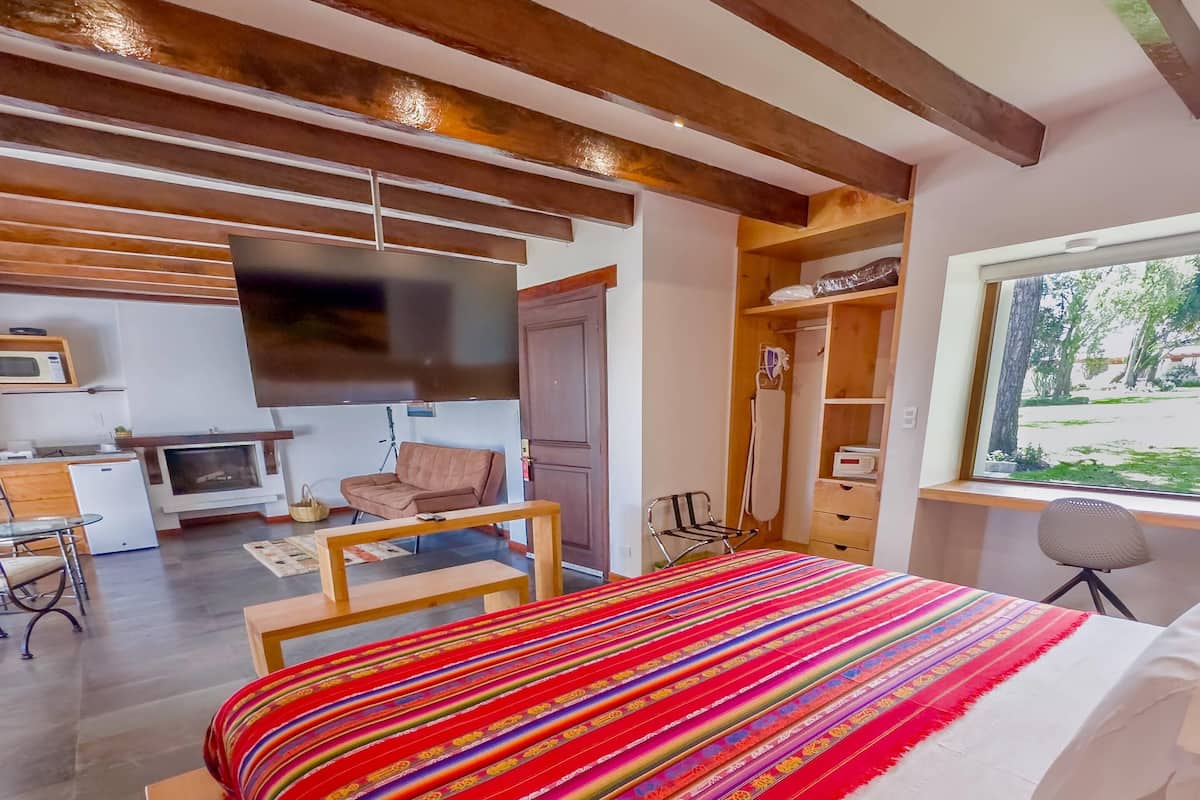 A bedroom with a bed, a TV, a desk, a chair, and a wardrobe.