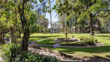 Un parque con una fuente, árboles y un césped bien cuidado.