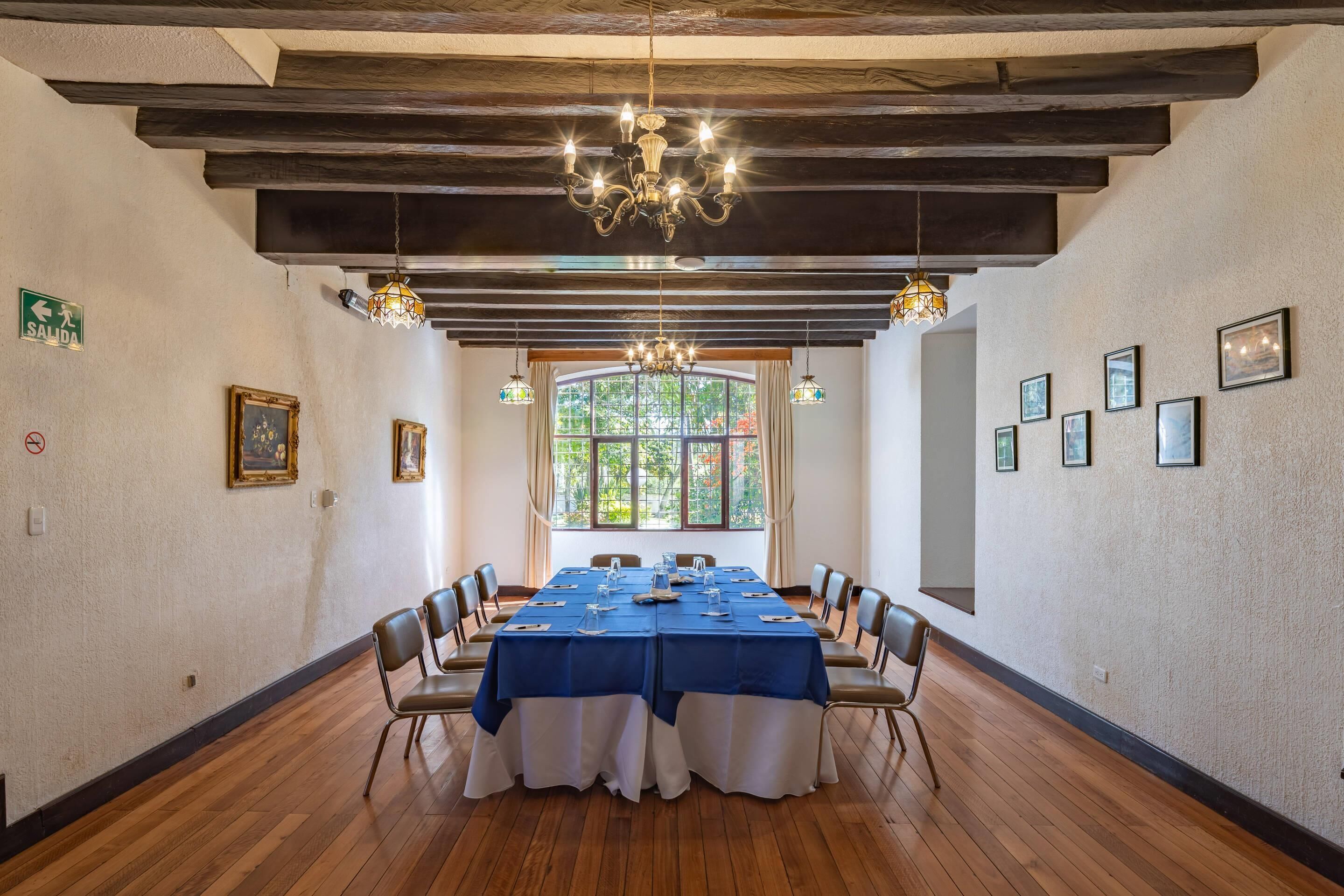 Un salón de conferencias con una larga mesa, sillas y un candelabro.