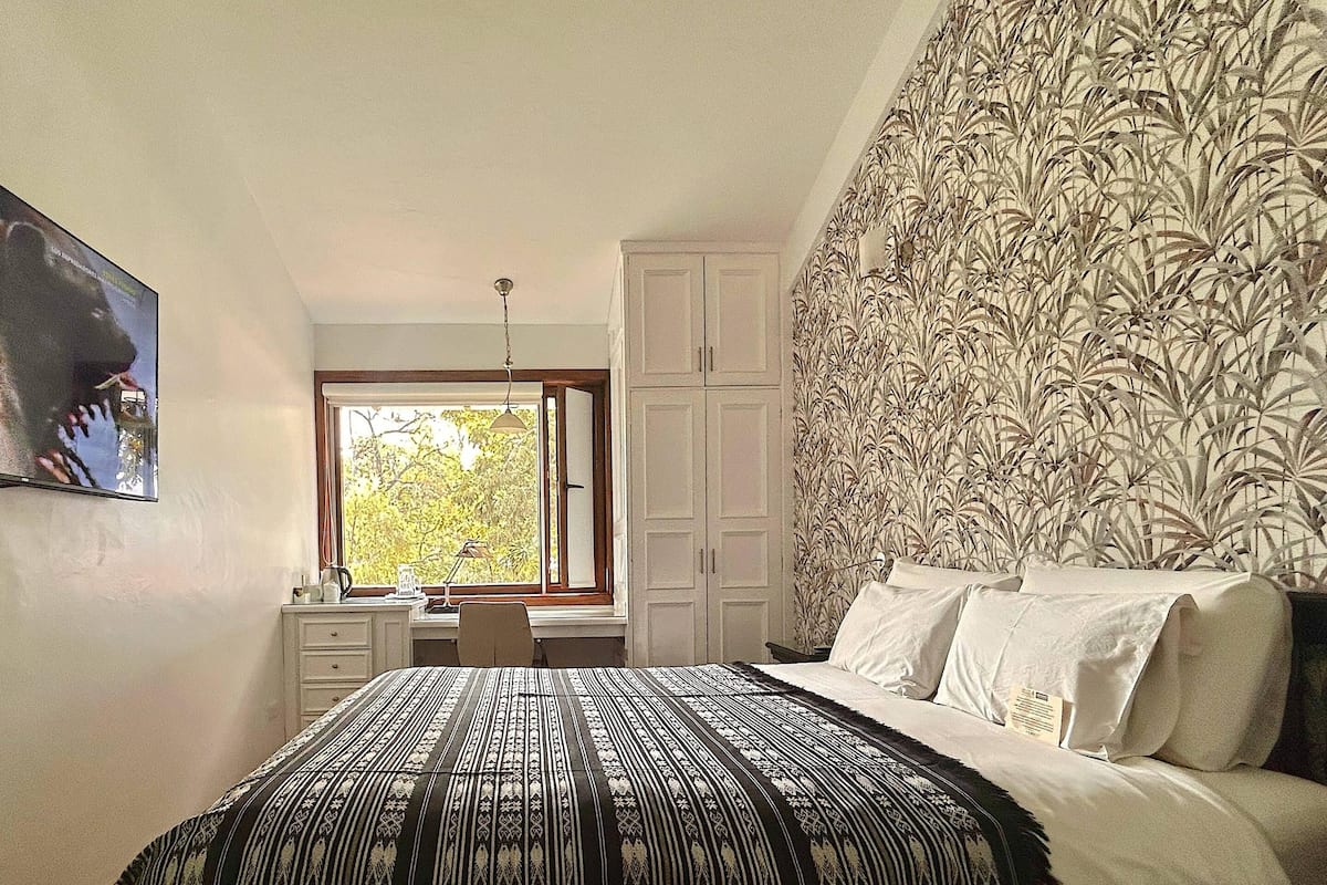 A bedroom with a bed, a desk, and a wardrobe.