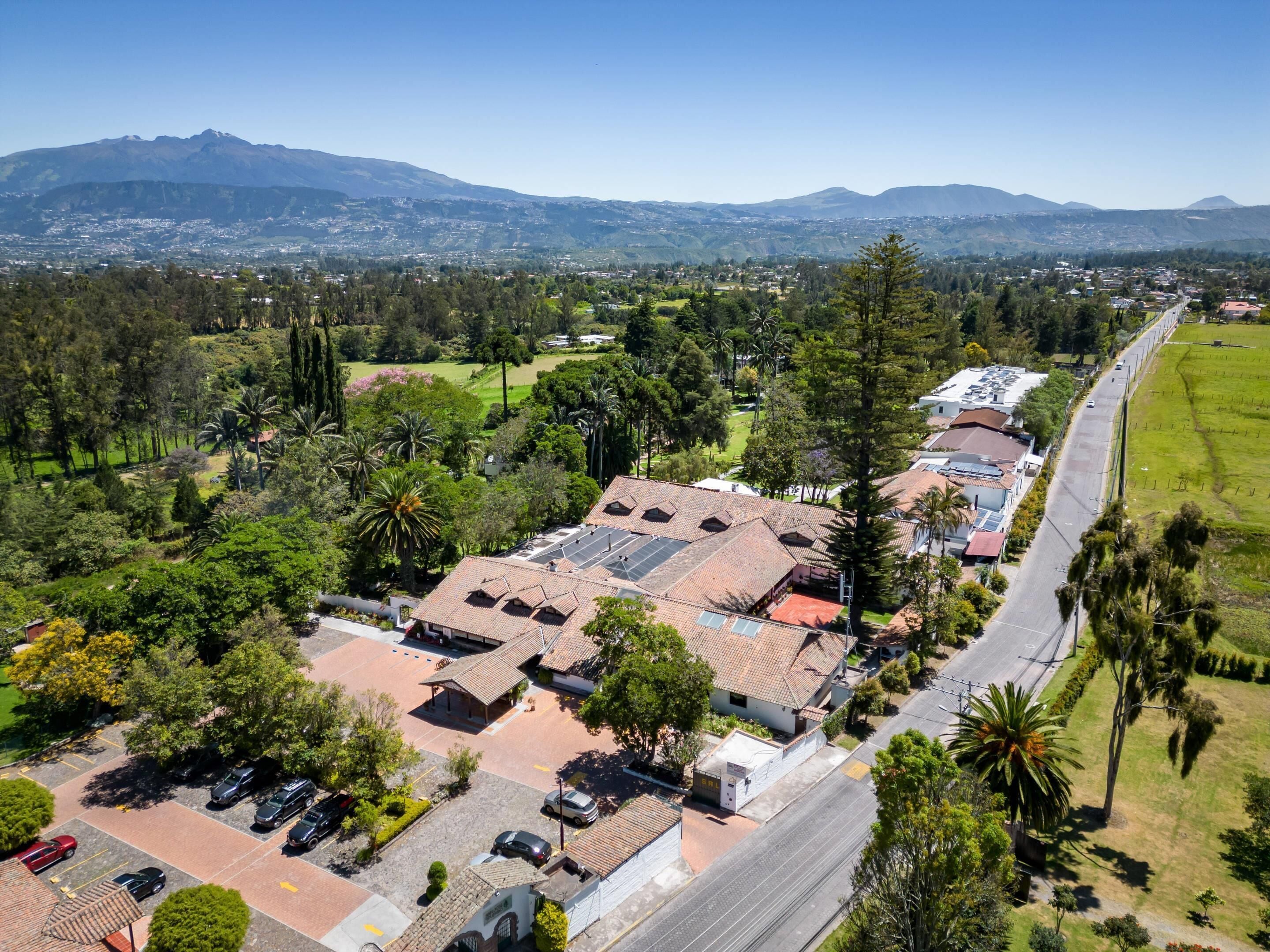 A residential area with a street, houses with tiled roofs, and a mountain range in the background.