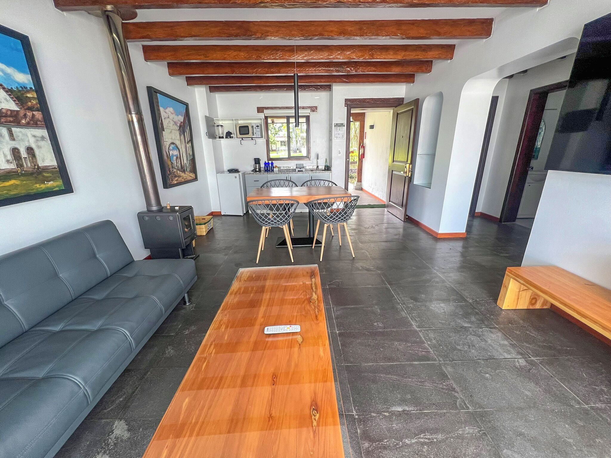 Una sala de estar moderna con un sofá, una mesa de centro de madera y un comedor con sillas y una mesa.