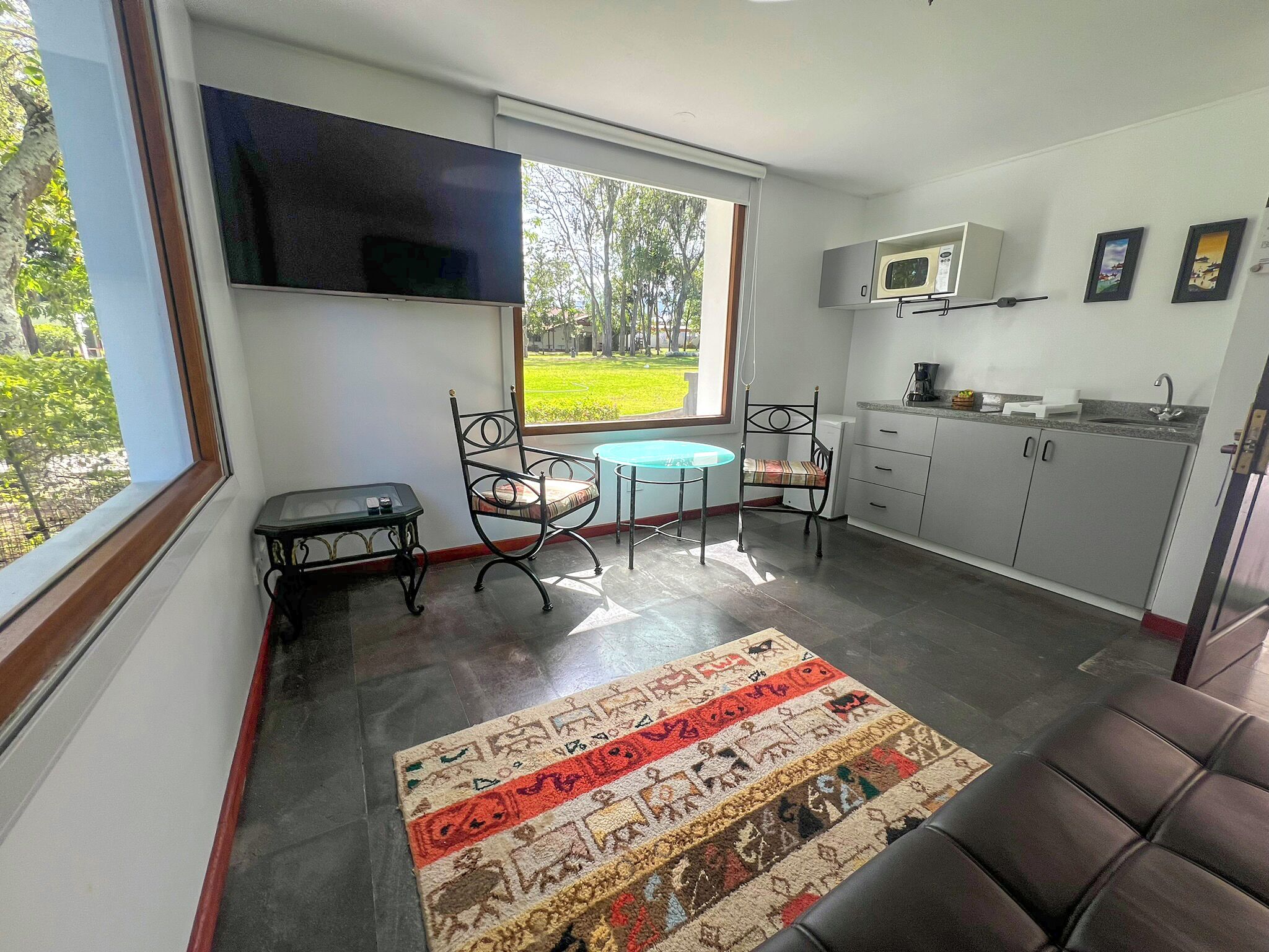 A compact kitchen with a TV, a small dining table, and a microwave.