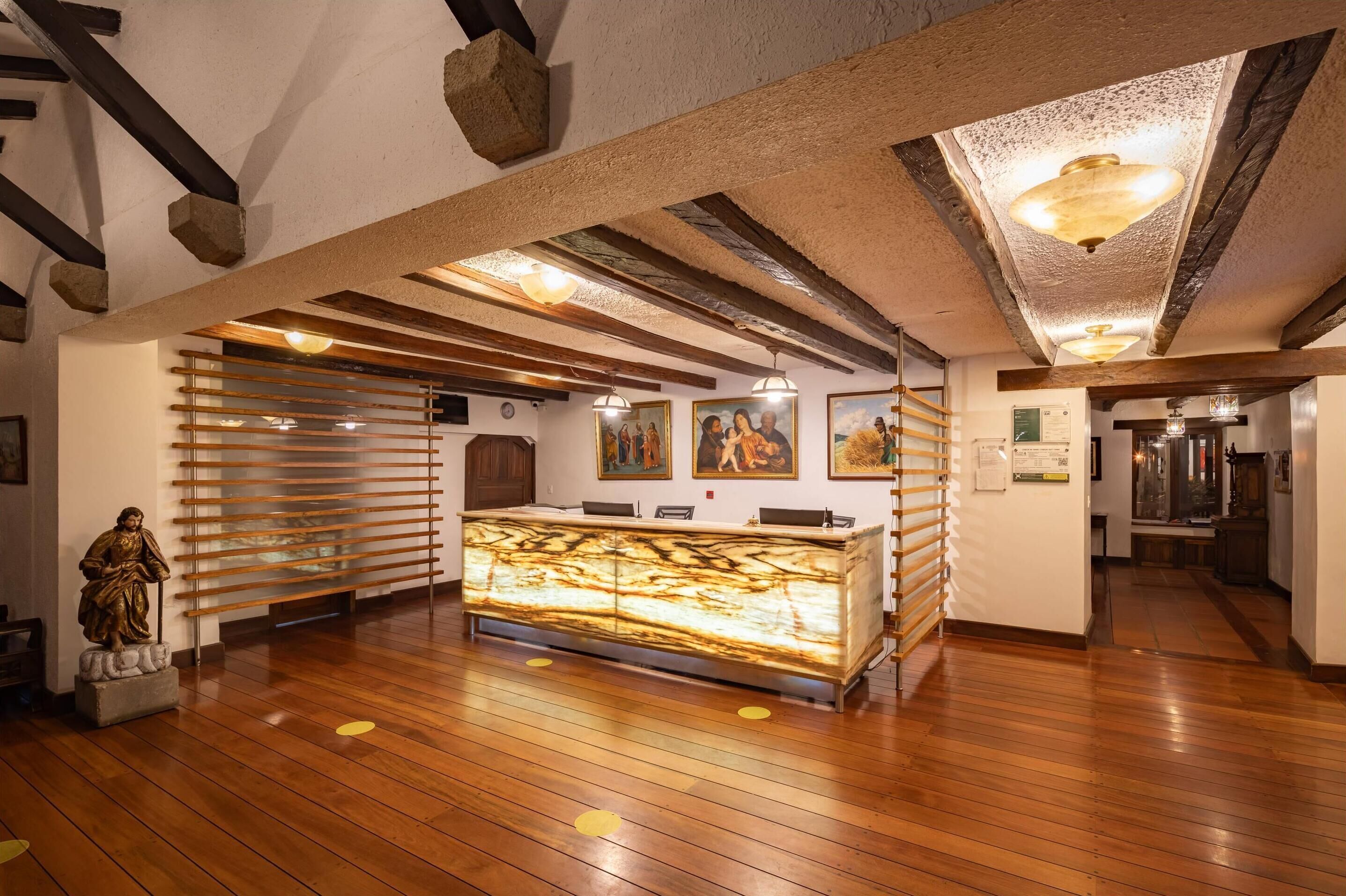 A reception area with a marble counter, wooden slats, and a statue.