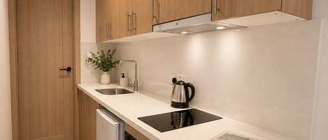 A modern kitchen with wooden cabinets, a dishwasher, an oven, a sink, and a kettle.