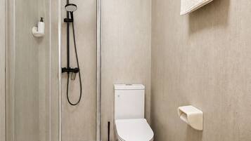 A modern bathroom with a glass-enclosed shower, a toilet, and a sink.