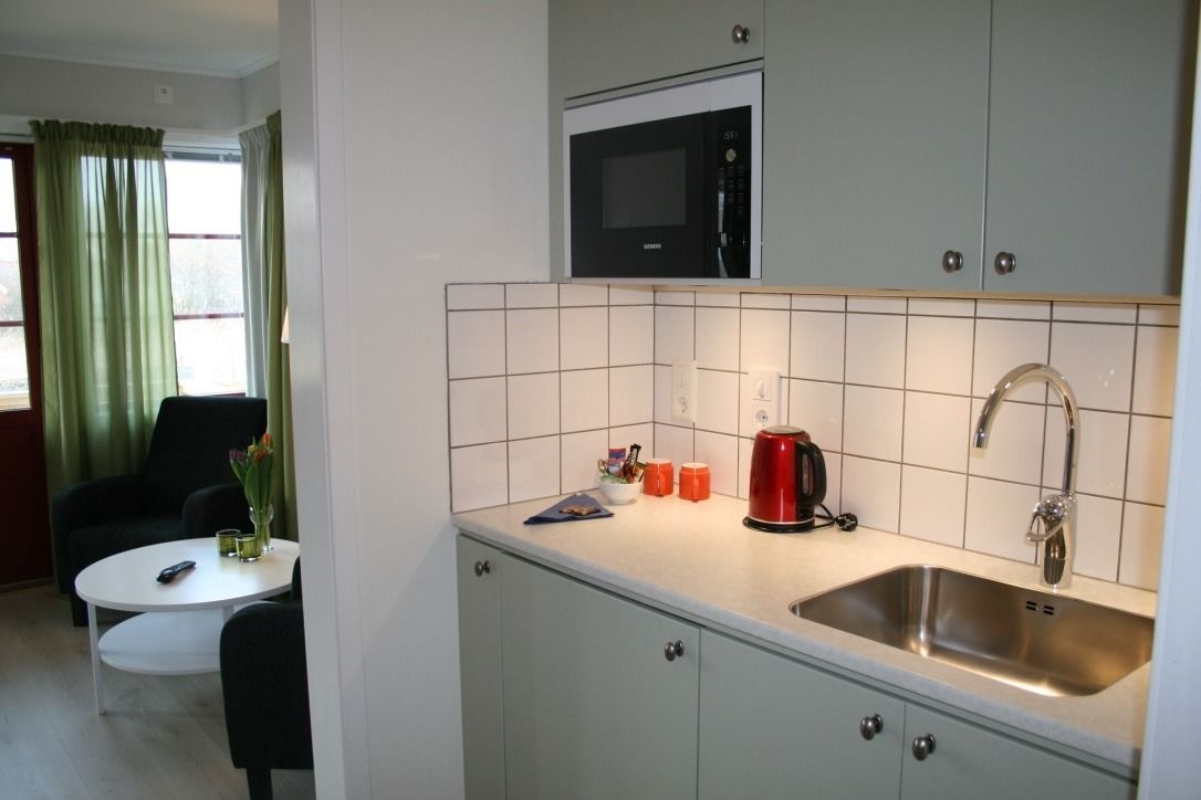 A compact kitchen with a microwave, sink, and a small dining area with a table and chairs.
