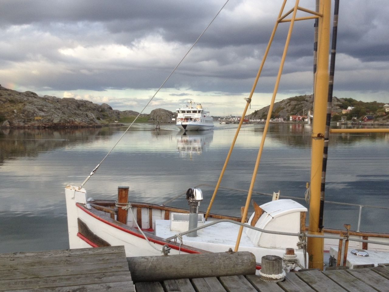 A boat docked at a pier with a view of a distant ship on the water.