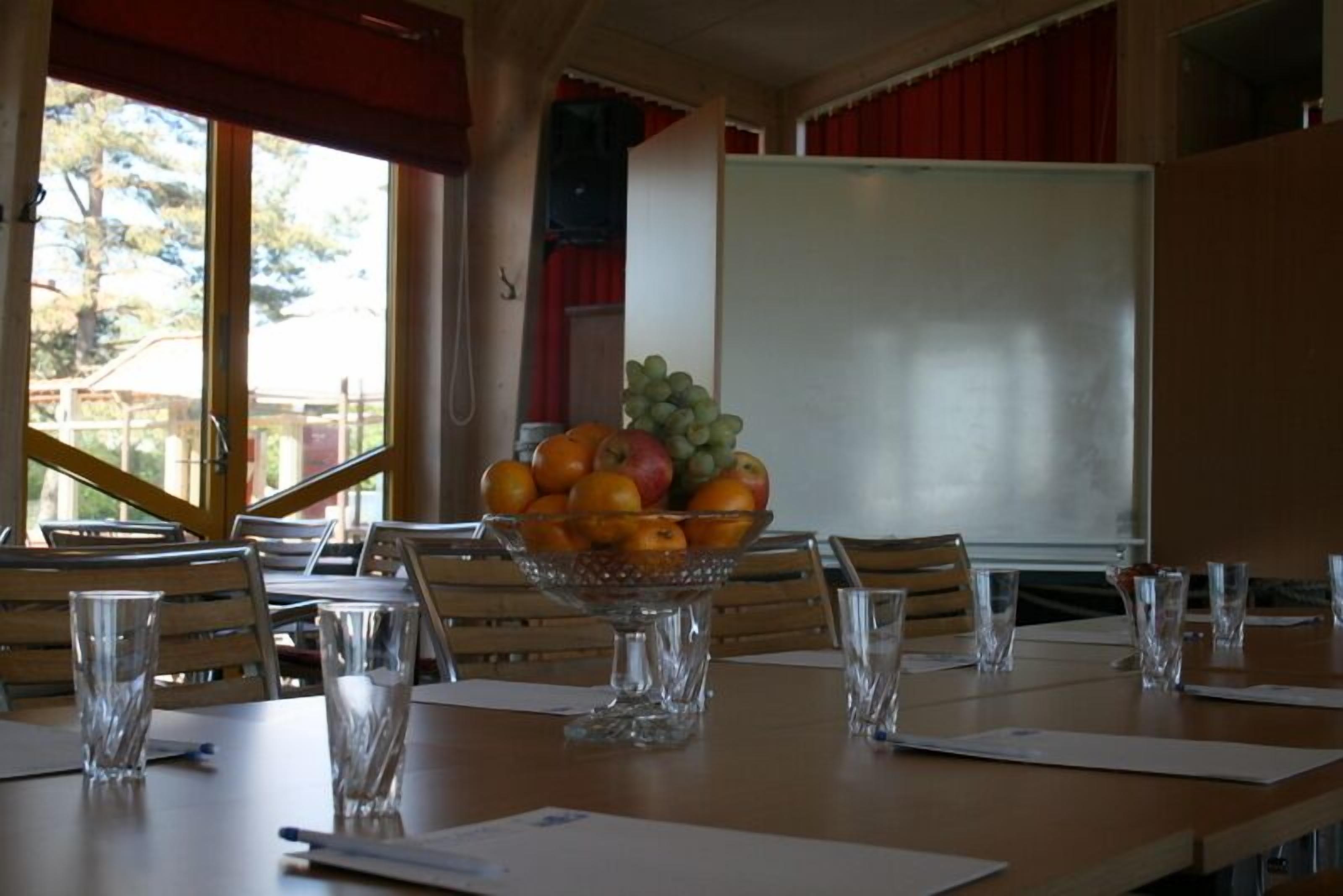 A conference room with a table set for a meeting, a fruit bowl, and a whiteboard.