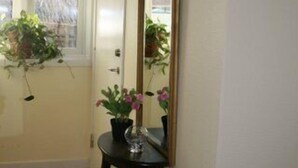 A hallway with a door, a mirror, and a small table with a vase of flowers. - Brännö Värdshus & Pensionat Baggen (Branno)