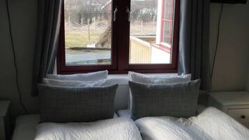 Un dormitorio con cama, ventana y vista al exterior.