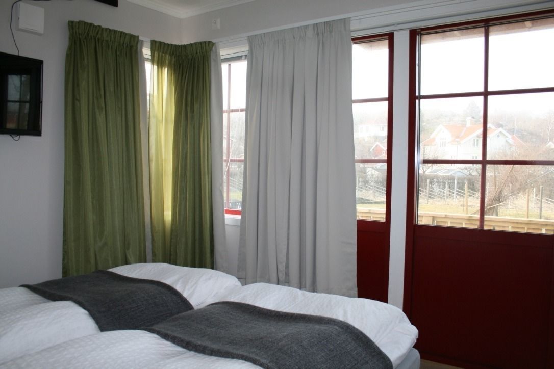 Ein Hotelzimmer mit zwei Betten, einem großen Fenster mit Vorhängen und Blick auf ein Gebäude.