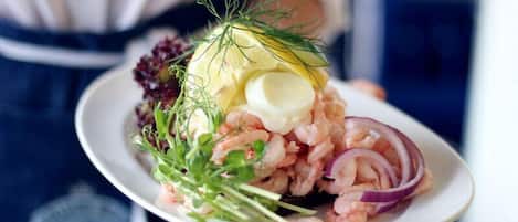 A plate of shrimp salad with dill, red onion, and a boiled egg.