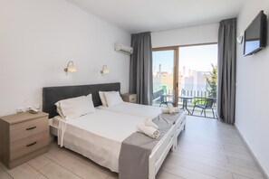 A hotel room with a double bed, bedside tables, a small desk, a chair, and a balcony with a table and chairs. - Belvita (Rhodes)
