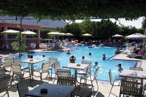 A pool area with multiple lounge chairs and umbrellas, surrounded by tables and chairs. - Belvita (Rhodes)